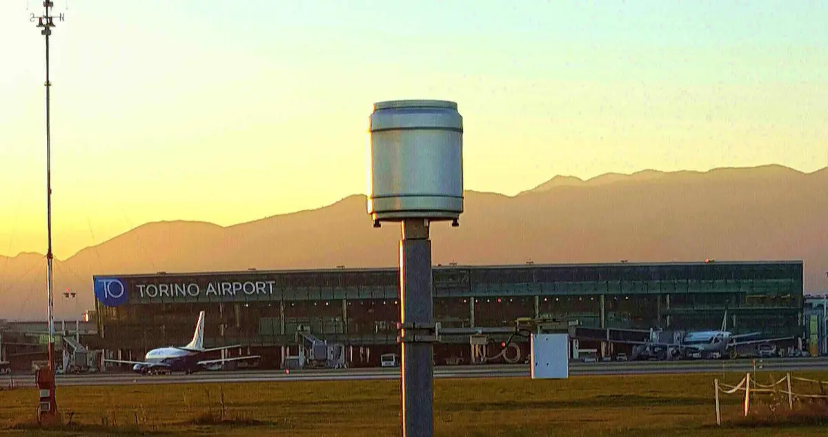 Il terminal dell'aeroporto di Torino al tramonto con le montagne sullo sfondo
