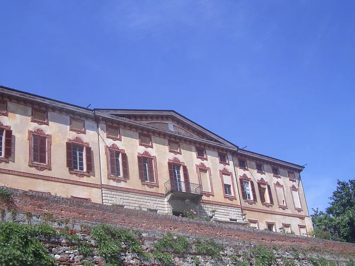 Palazzo rosa e giallo con persiane rosse su una collina ad Azeglio