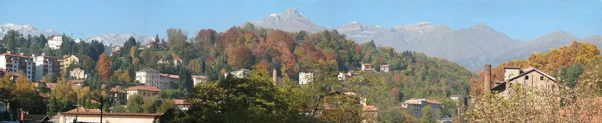 Veduta di Biella sulla collina con alberi autunnali e montagne sullo sfondo