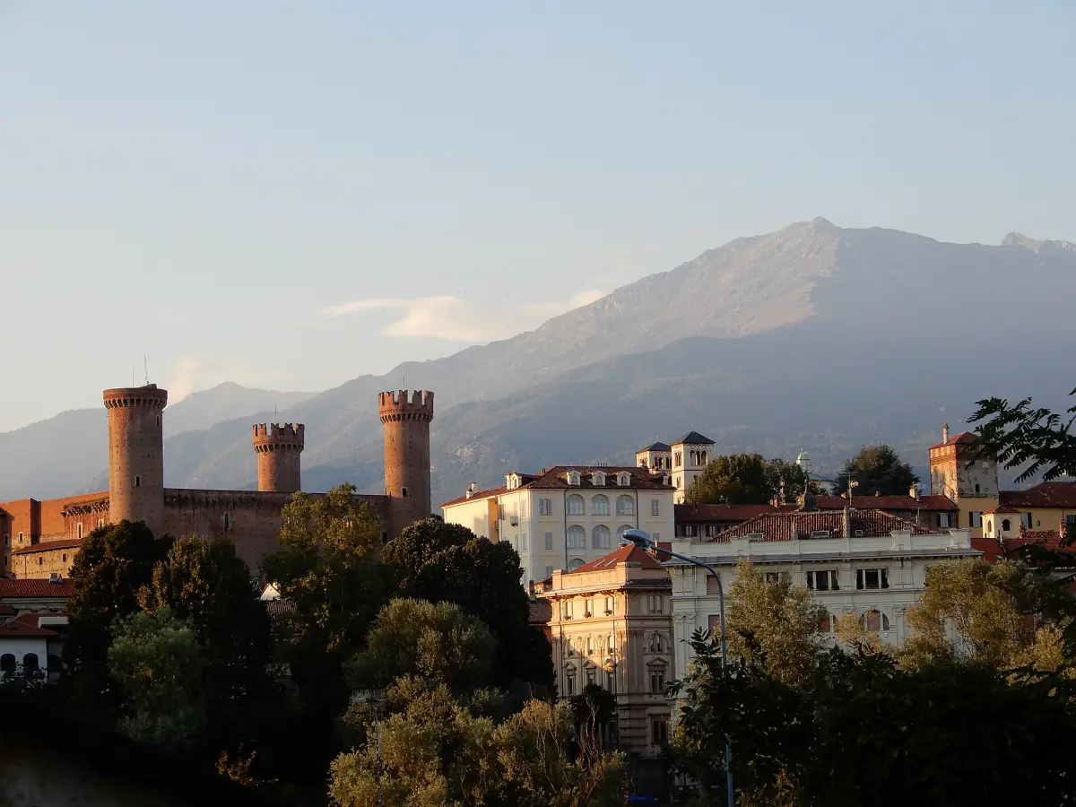 Il castello di Ivrea con le torri sopra gli alberi e una montagna dietro