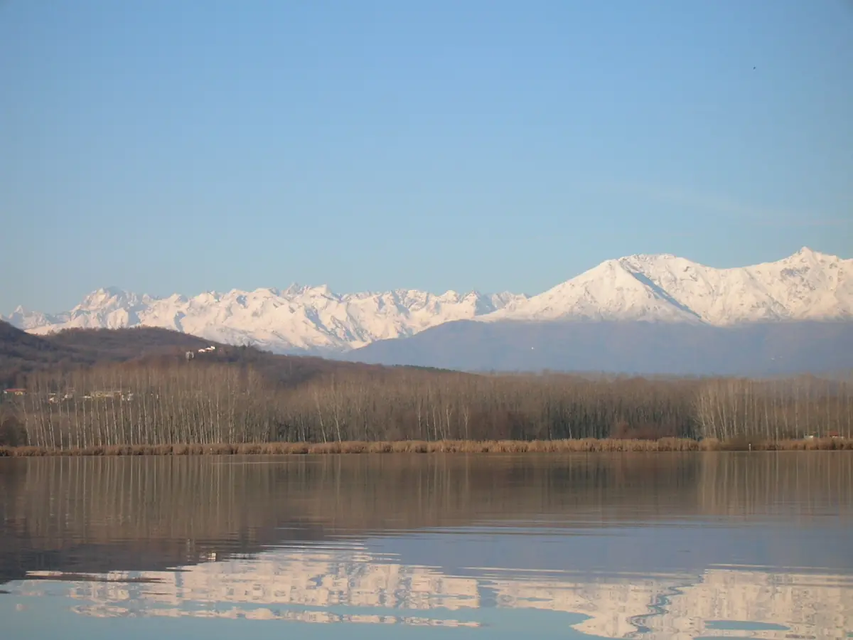 Le Alpi innevate riflesse nell'acqua calma del Lago di Candia